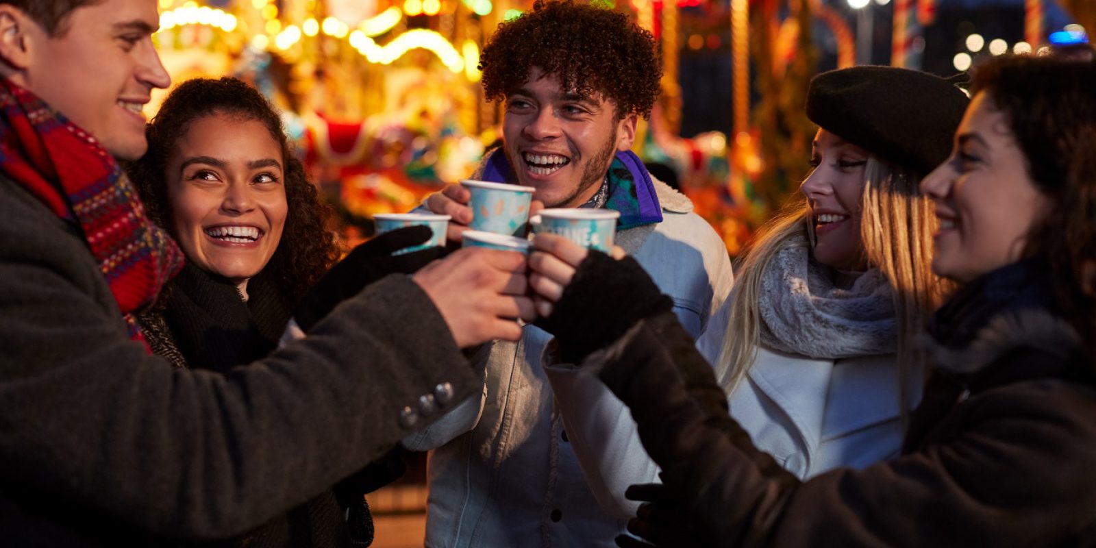 A group of friends enjoying a warm festive drink at a Christmas market