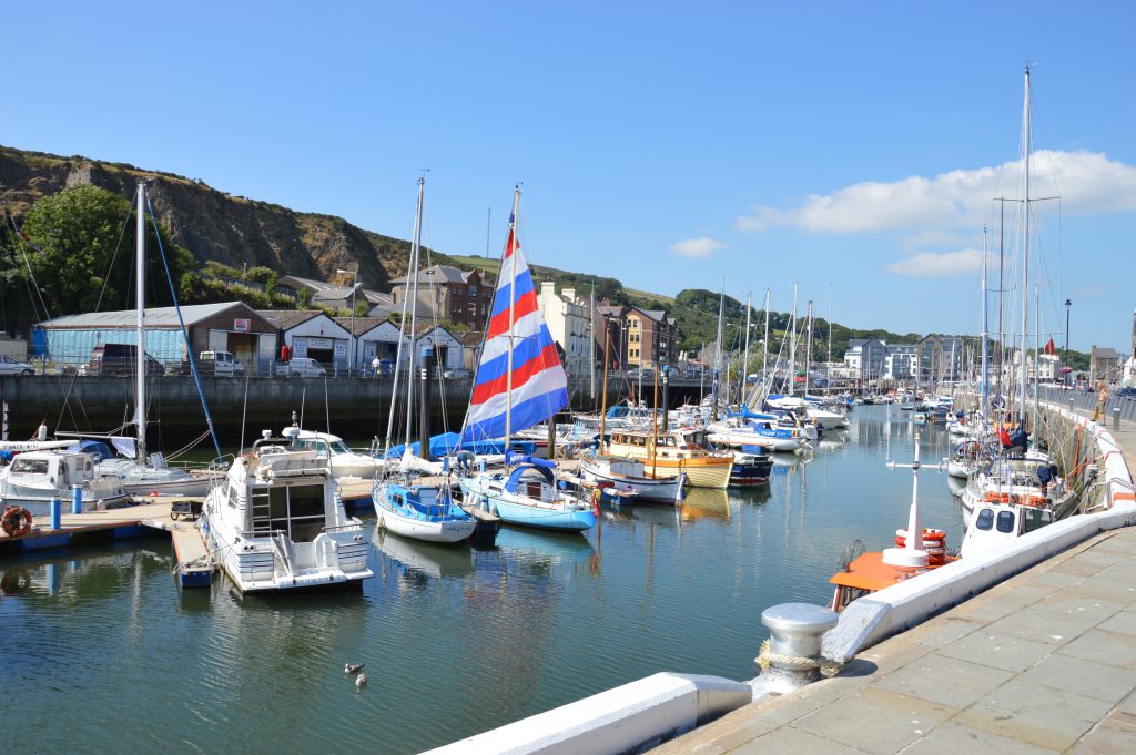 A view of Douglas Quayside with lots of small boats parked up on a sunny day with a blue sky. 