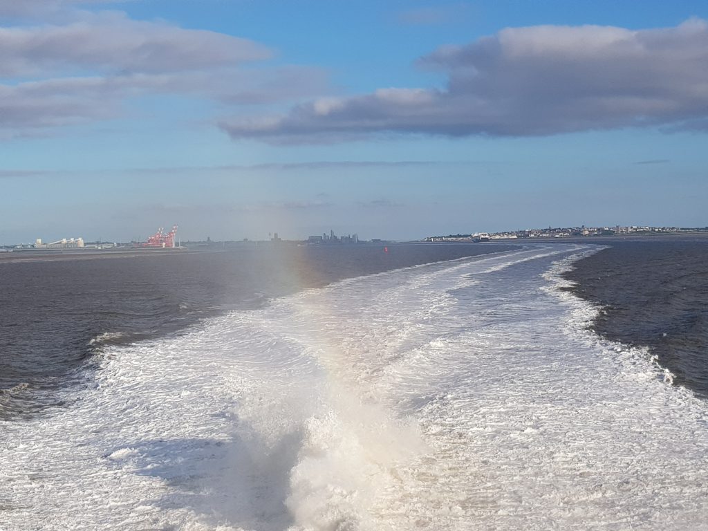 The view from the back of the Steam Packet Company vessel Manannan, showing sea waves with Liverpool in the background 