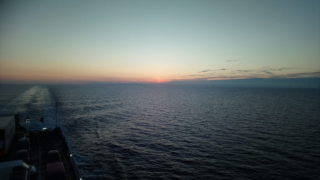 View from the back of Steam Packet Company vessel Ben-my-Chree with miles of sea on display in addition to a orange sunset and blue sky 