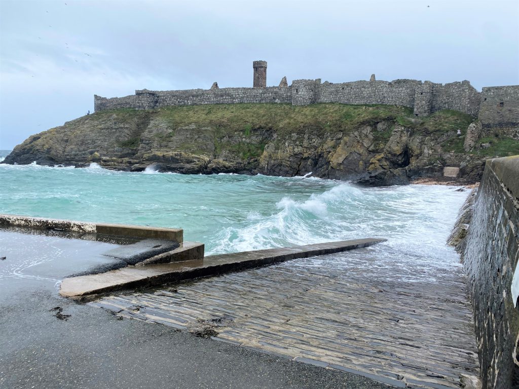 Waves crashing at Fenella Beach, Peel, Isle of Man with Peel Castle in the background