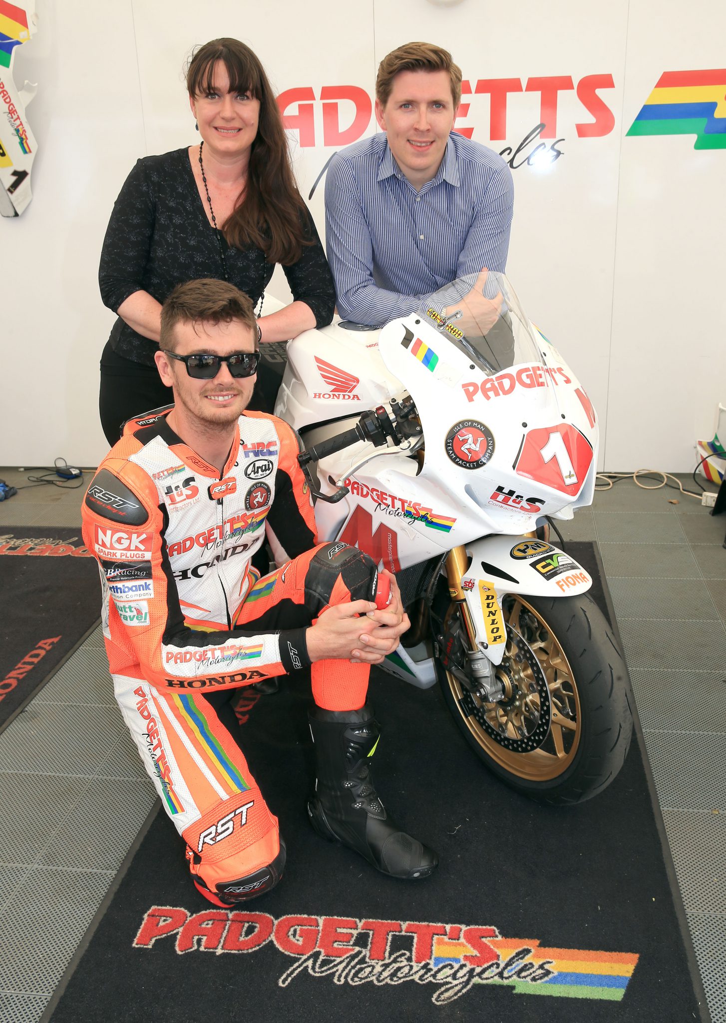 Conor Cummins in orange leathers with his bike and two members from the Isle of Man Steam Packet Company