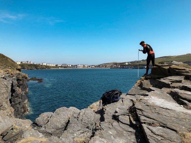 Someone in a wet suit climbing along the Island's coastal rocks