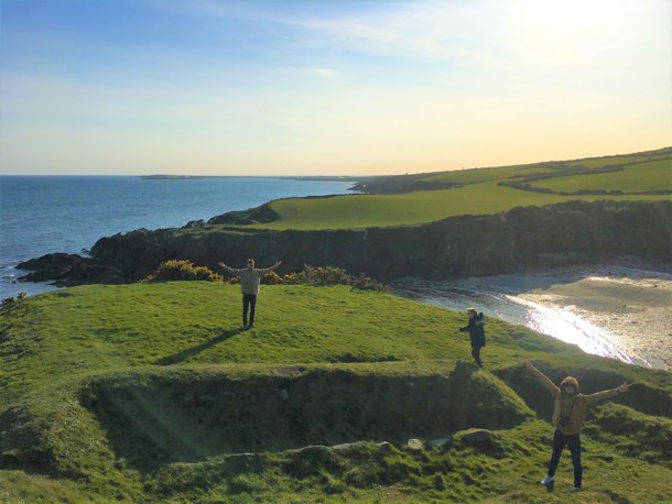 Three people wrapped up in coats on the Isle of Man coastline
