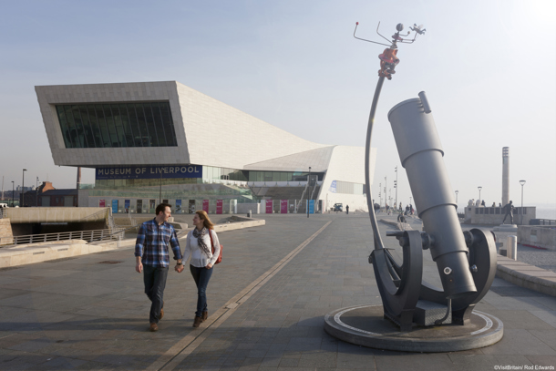 Couple holding hands walking past the Museum of Liverpool